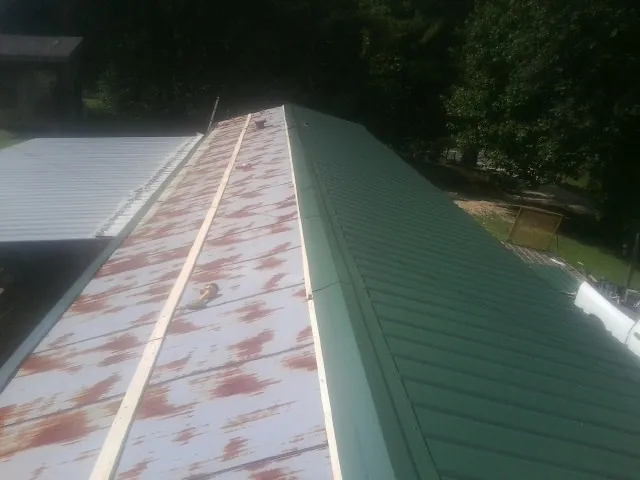 Old rusted panels beside newly installed green metal roofing — Wind Damage Roof Repair by Roofing Brothers in Apalachicola