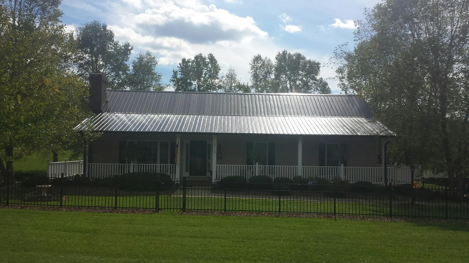 Gray metal roof on a brick ranch with a full width front porch — Gutter Guard Installation work by our crew in Apalachicola