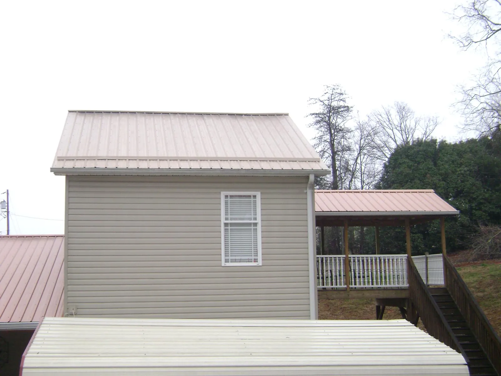 Tan metal roofs on a two story addition and attached porch, from a Roof Replacement job in Apalachicola