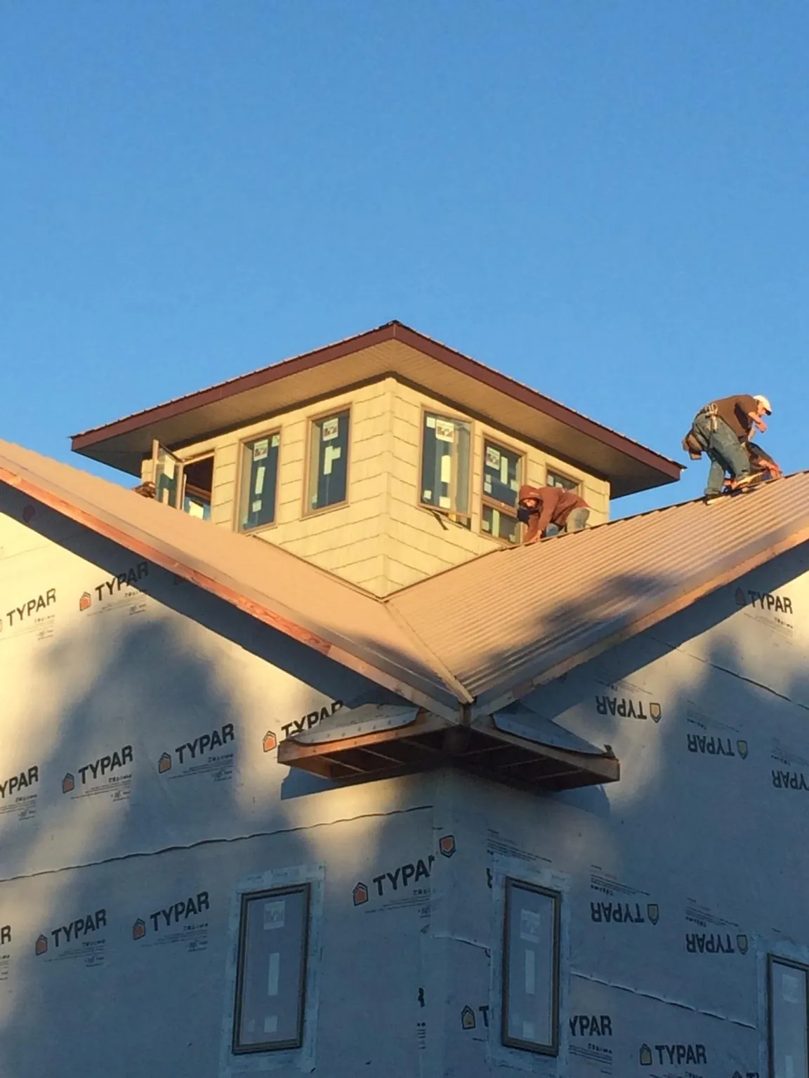 Roofers working around a rooftop cupola on a new metal roof at sunset — Roof Waterproofing in Apalachicola by Roofing Brothers